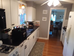 Enjoy cooking in this fully equipped kitchen with a gas stove and refrigerator, leading to a dining area with a table and chairs.