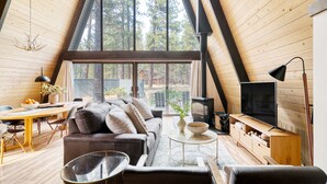 Un intérieur chaleureux, avec des éléments en bois, une grande fenêtre, un canapé, une table à manger et un téléviseur.