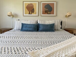 A neatly made bed with a patterned bedspread, two pillows, and a blanket. There are two framed artworks above the bed, and two bedside lamps on either side. - Perfect Palm Springs Getaway with Mountain Views (Palm Springs)