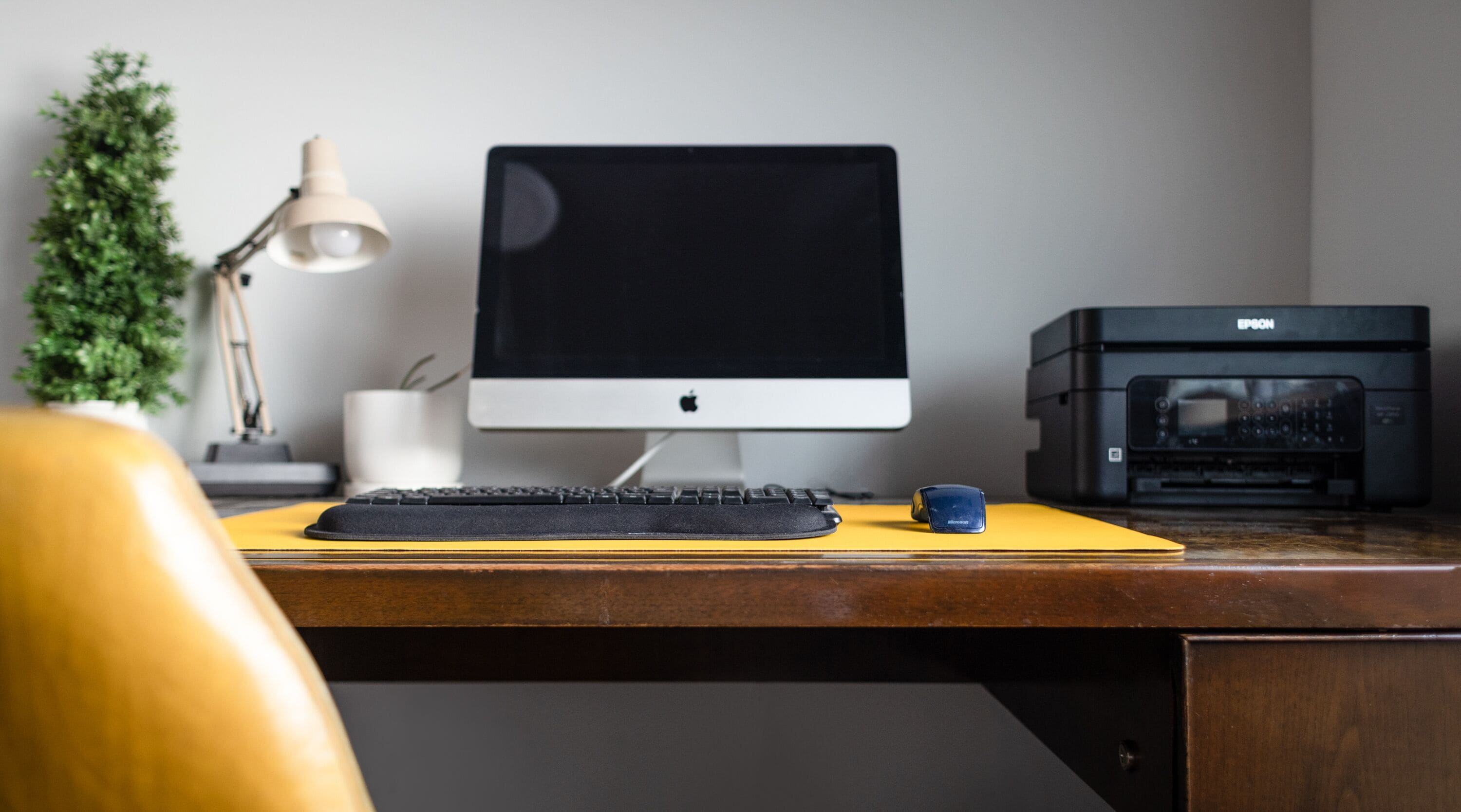 Un bureau avec un écran d’ordinateur, un clavier, une souris et une imprimante.