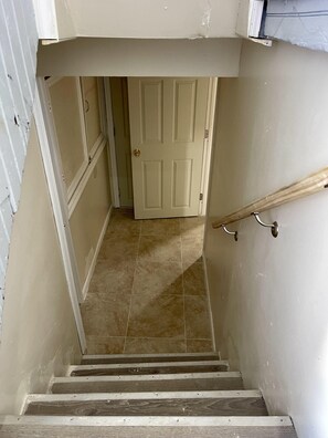 Stairs lead to a door at the top, with a handrail on the right.