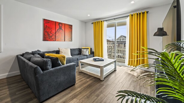 A modern living room with a grey sofa, a white coffee table, and yellow curtains. - Beach House Steps away from the Boardwalk and Beach with Ocean Views at Seaside… (Seaside Heights)