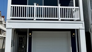 A two-story building with a white exterior, a garage, and a balcony with white railings. - Beach House Steps away from the Boardwalk and Beach with Ocean Views at Seaside… (Seaside Heights)