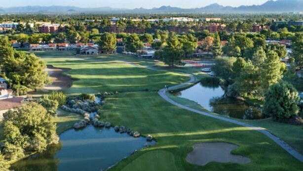 A golf course with water hazards, sand bunkers, and a well-maintained fairway.