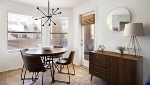 A dining area with a round table, chairs, a ceiling light fixture, a cabinet, and a mirror.