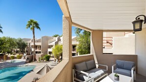 A poolside area with a pool, lounge chairs, and a small table with a plant.