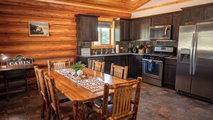 A cabin-style kitchen with wooden cabinetry, a stainless steel refrigerator, an oven, and a microwave.