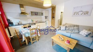 A compact living space with a kitchenette, a dining area with a table and chairs, a sofa, and a coffee table.