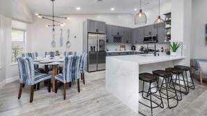 A modern kitchen with grey cabinets, a large island, and bar stools. - Oasis in the Desert w/ Heated Pool Fully Renovated (North Las Vegas)