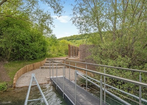 A wooden bridge over a stream with metal railings, surrounded by greenery and trees. - 2 bedroom accommodation in Halling (Halling)