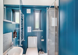 A bathroom with a white sink, a toilet, a shower, and a window.