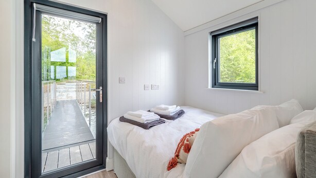 Een slaapkamer met een bed, een raam en een deur naar een buitengebied.