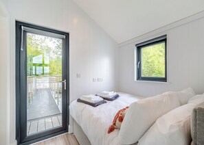 A bedroom with a bed, a window, and a door leading to an outdoor area.
