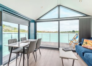 A modern room with a dining table, chairs, a sofa, and a view of the water. - 2 bedroom accommodation in Halling (Halling)
