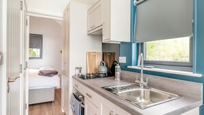 A compact kitchenette with a sink, stove, and window.