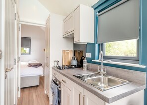 A compact kitchenette with a sink, stove, and window. - 1 bedroom accommodation in Halling (Halling)