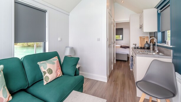 A compact room with a green sofa, a small table, a bed, a kitchenette, and a view of the outdoors. - 1 bedroom accommodation in Halling (Halling)