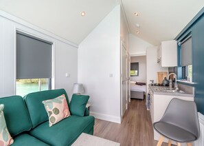 A compact room with a green sofa, a small table, a bed, a kitchenette, and a view of the outdoors. - 1 bedroom accommodation in Halling (Halling)