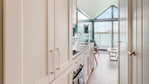 A modern kitchen with a large window, a dining area with a view, and a balcony.
