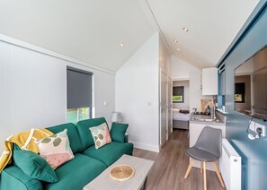 A compact living space with a green sofa, a small dining table, a kitchenette, and a bed in the background. - 1 bedroom accommodation in Halling (Halling)