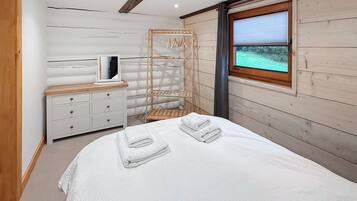 A bedroom with a bed, a dresser, a mirror, and a window with a view.