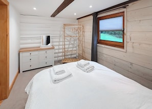 A bedroom with a bed, a dresser, a mirror, and a window with a view.