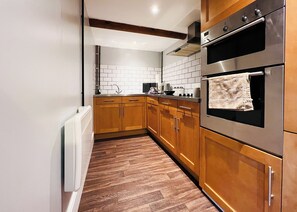 Une cuisine moderne avec des meubles en bois, des appareils électroménagers en acier inoxydable et un dosseret carrelé.