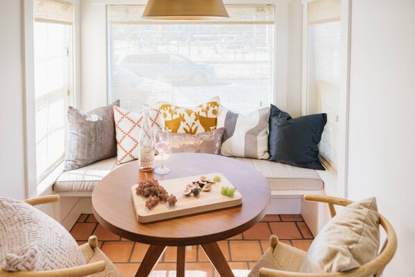 A cozy seating area with a round table, a bottle of wine, and a glass on the table. - Impeccable Location and Quality, High-End Upgrades Throughout, Walk to Everything, Across from Park (Newberg)