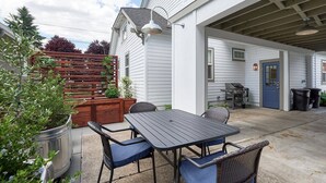 En udendørs patio med et bord og stole, et træhegn og en blå dør.