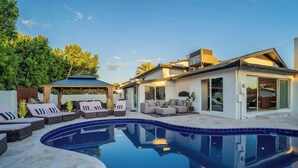 Une maison moderne dotée d’une piscine, de mobilier d’extérieur et d’un patio couvert.