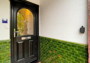 A black door with a glass panel, white brick wall, and green tiled lower half. - Poets Apartment By My Getaways (Worthing)