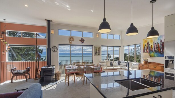 A spacious kitchen with a large island, a dining area with a view, and a living room with a sofa and a coffee table.