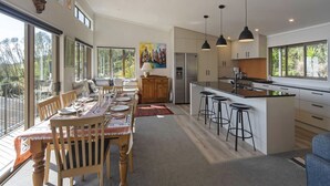 A modern kitchen with a central island, bar stools, and a dining area with a bench and table.