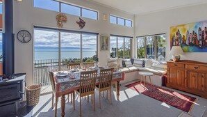 A dining area with a view of the sea, a large window, and a painting on the wall.