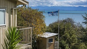 A wooden house with a balcony overlooking a lake and mountains.