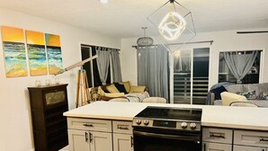 Une cuisine moderne dotée d’un îlot central, d’un four encastré et d’un coin repas avec un canapé et des rideaux.
