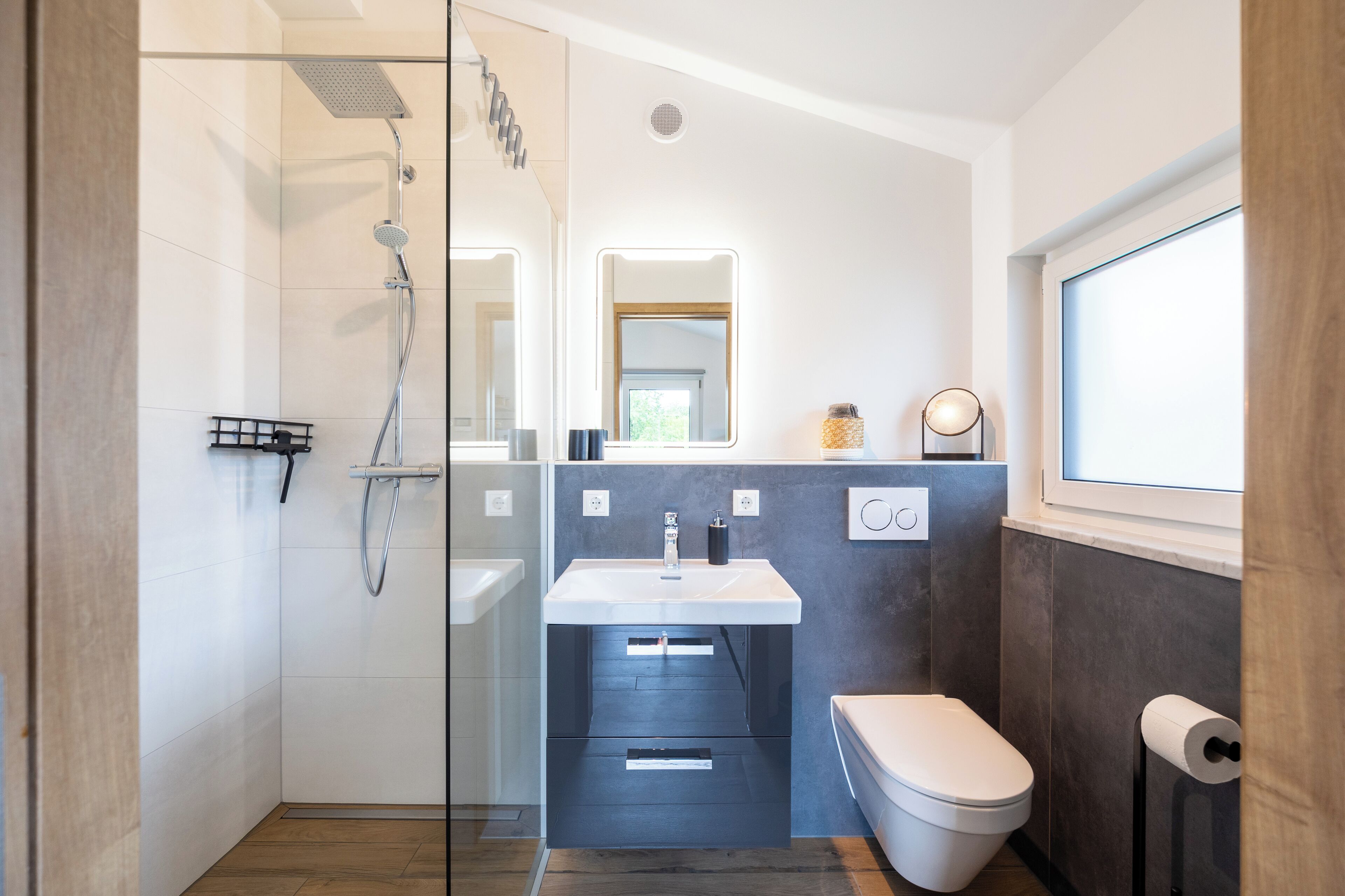 Une salle de bain moderne avec une douche à parois de verre, un lavabo blanc et des toilettes.