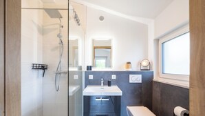 Une salle de bain moderne avec une douche à parois de verre, un lavabo blanc et des toilettes.