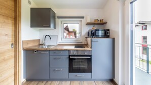 Une cuisine moderne avec des meubles gris, un four encastré, un micro-ondes et une fenêtre au-dessus de l’évier.