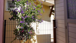 Un bâtiment doté d’un balcon, d’une clôture en métal et d’un pot de fleurs contenant des plantes aux fleurs violettes.