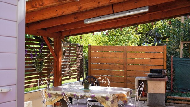 Une terrasse extérieure avec une table et des chaises, une pergola en bois et une clôture en bois.