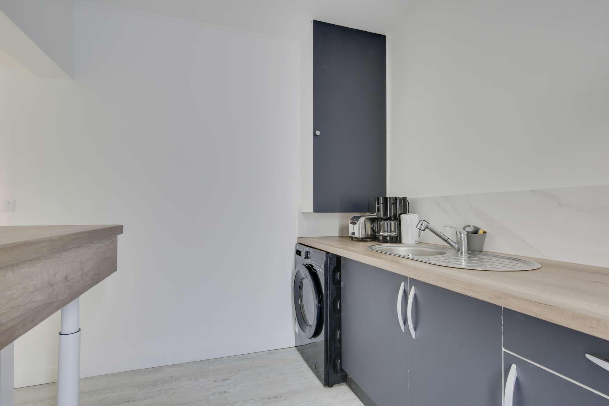 A compact kitchen with a washing machine, a sink, and a countertop.