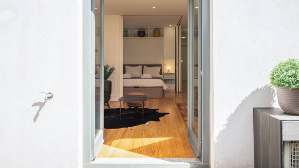 A modern bedroom with a bed, bedside tables, and a small seating area. - PATIO DE FLORES - Beautiful apartment with patio located in downtown Porto (Porto)
