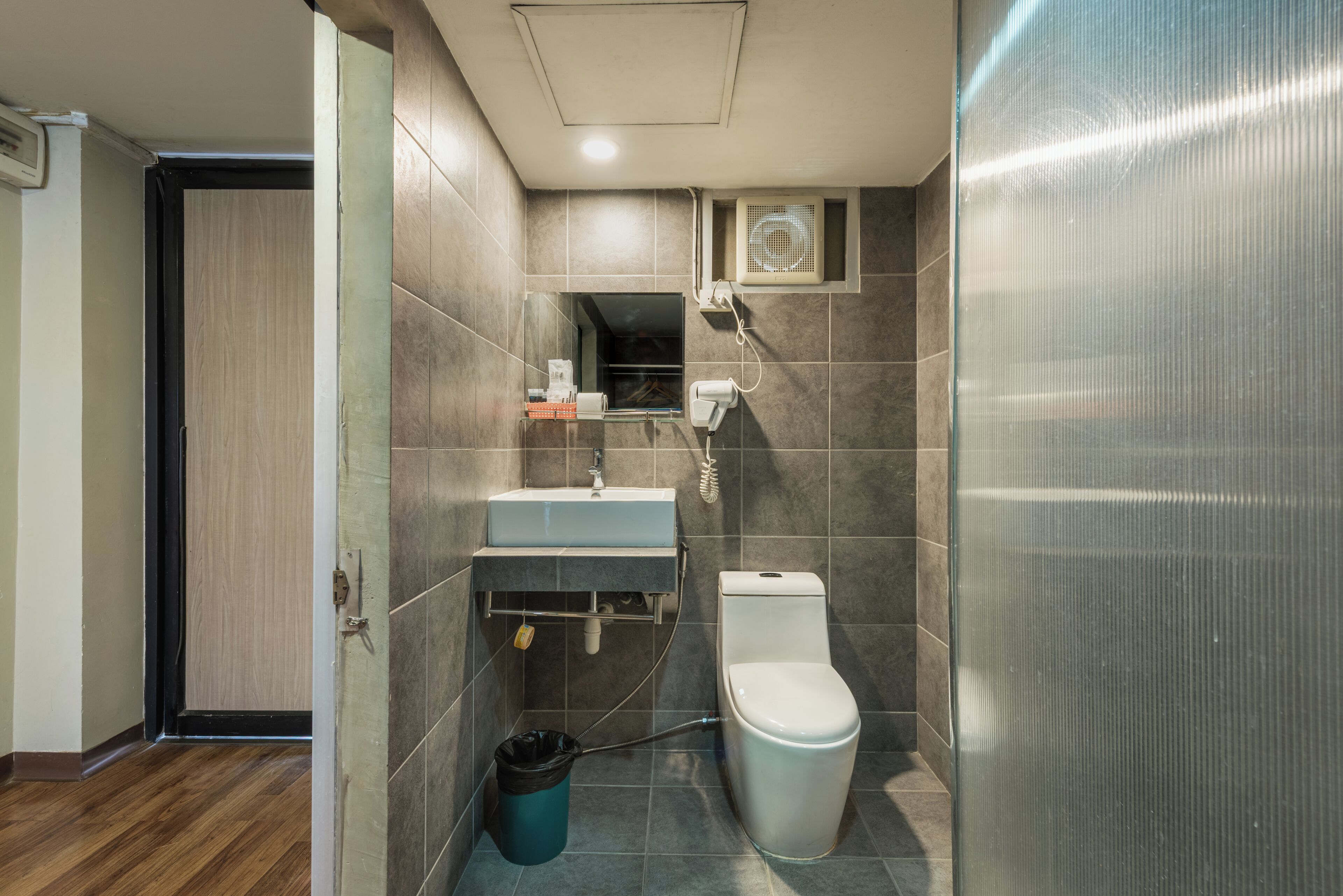 A bathroom with a toilet, sink, and mirror.
