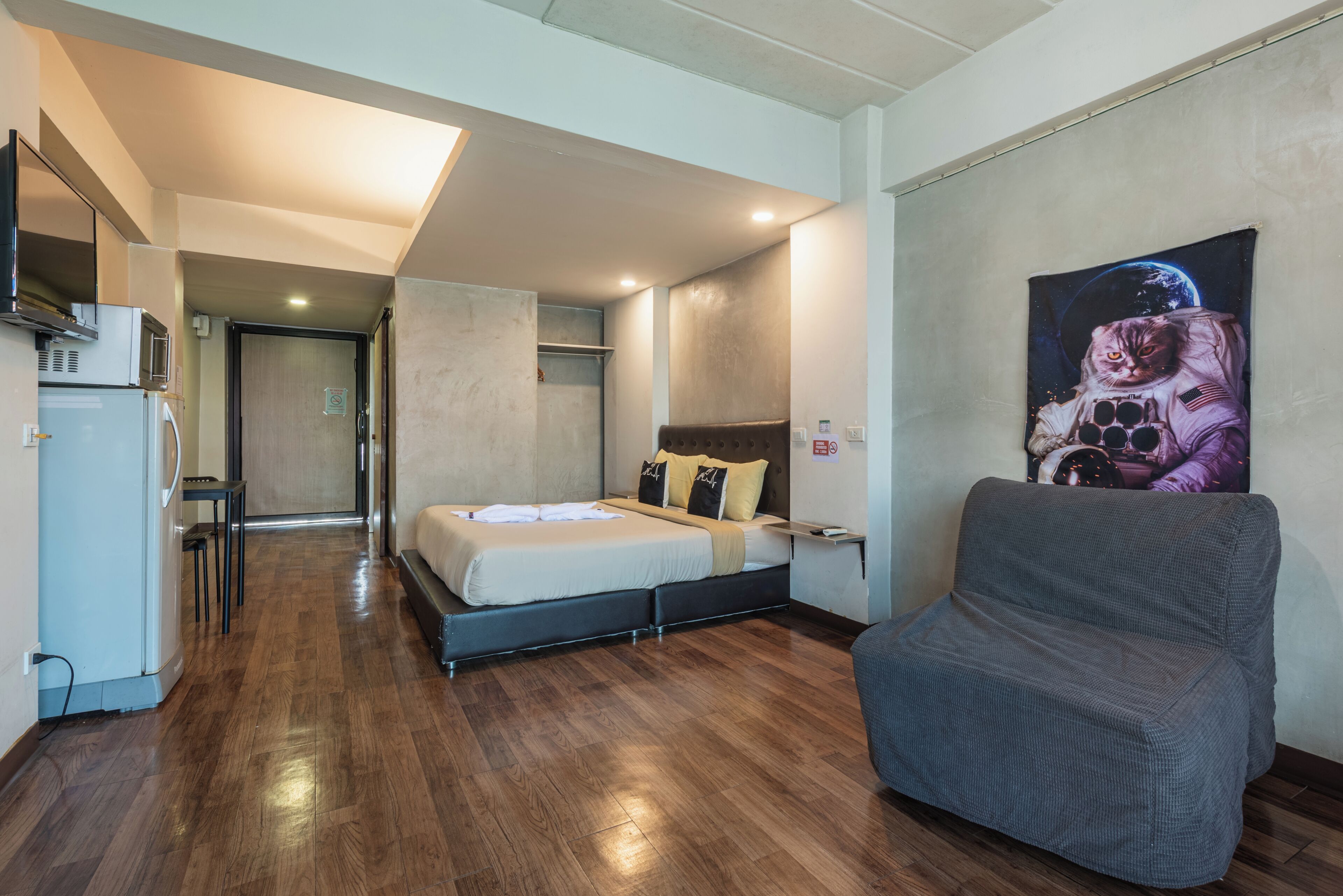 A modern room with a bed, a sofa, a microwave, and a refrigerator.