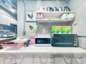 A kitchen with a microwave, toaster, and various kitchen utensils on the counter. - Bkk39 Airport hotel (Bang Phli)