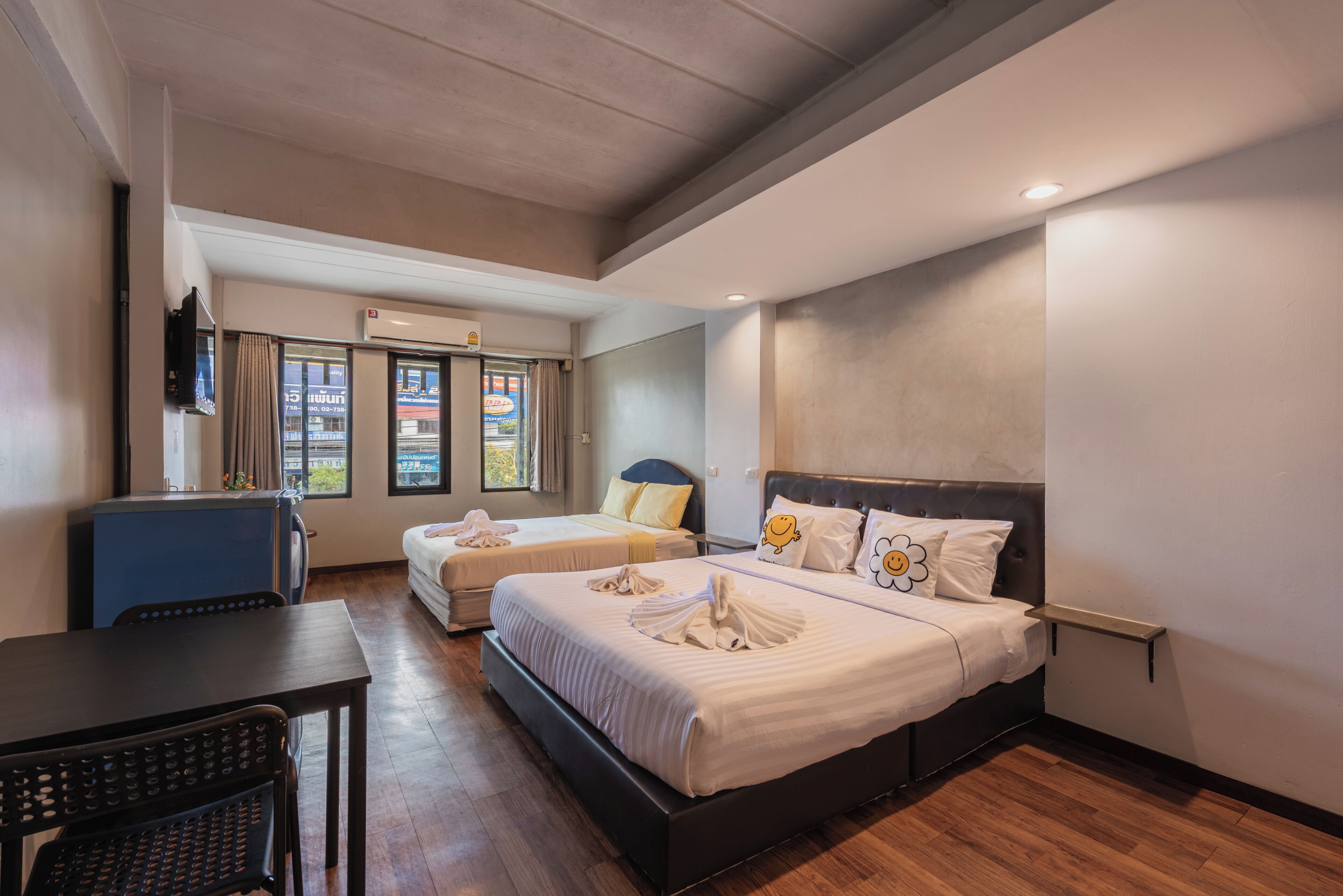 A hotel room with two beds, a desk, and a chair.
