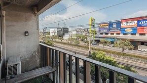 Un balcon avec un mur en béton, une lanterne noire et une rambarde en métal.