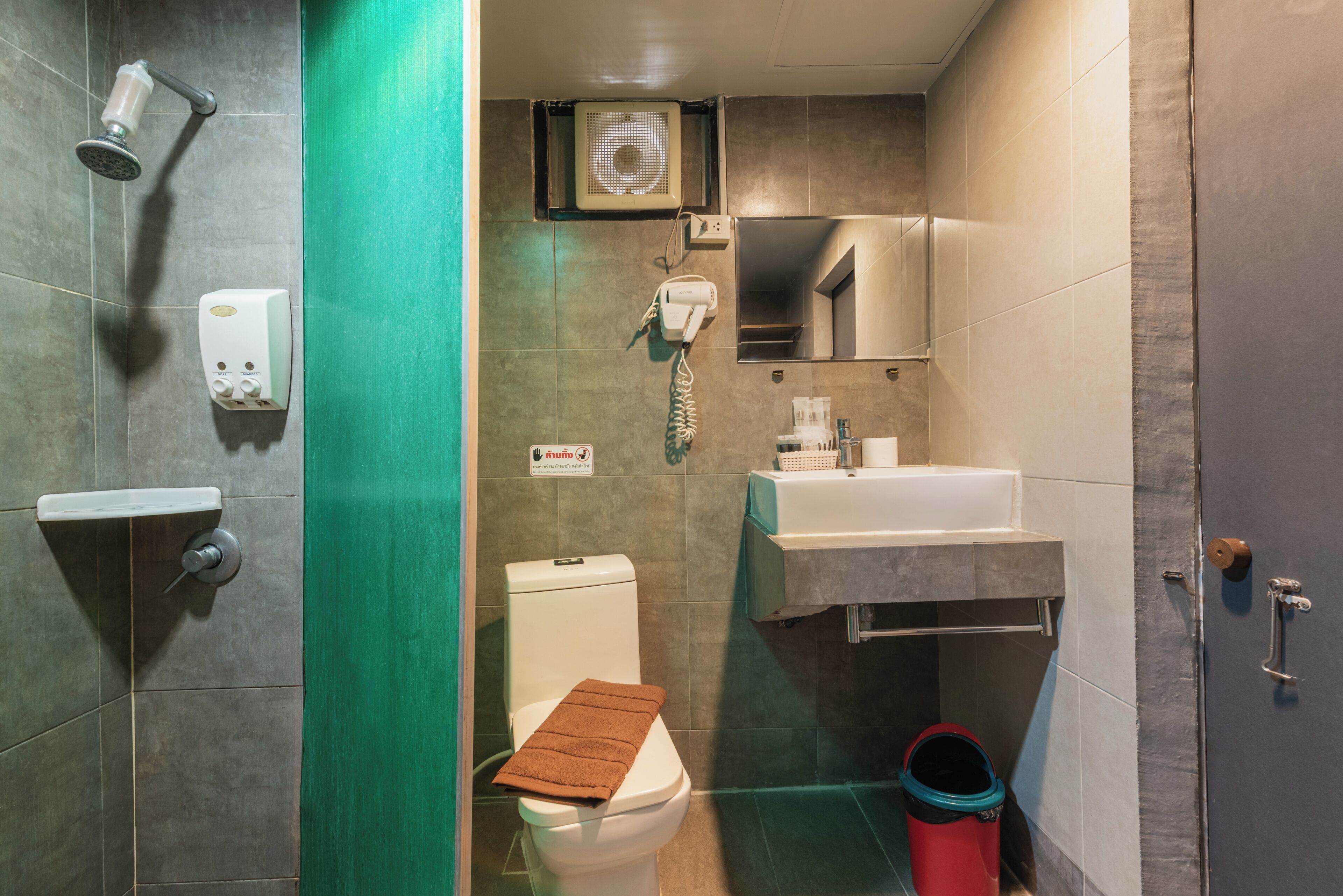 A bathroom with a shower, toilet, sink, and a mirror.