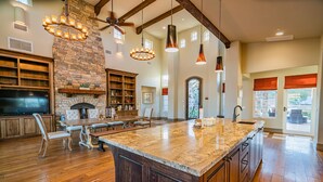 A spacious kitchen with a large island, wooden cabinets, and a stone fireplace. - Mansion on De Portola with Vineyard and Mountain view (Temecula)